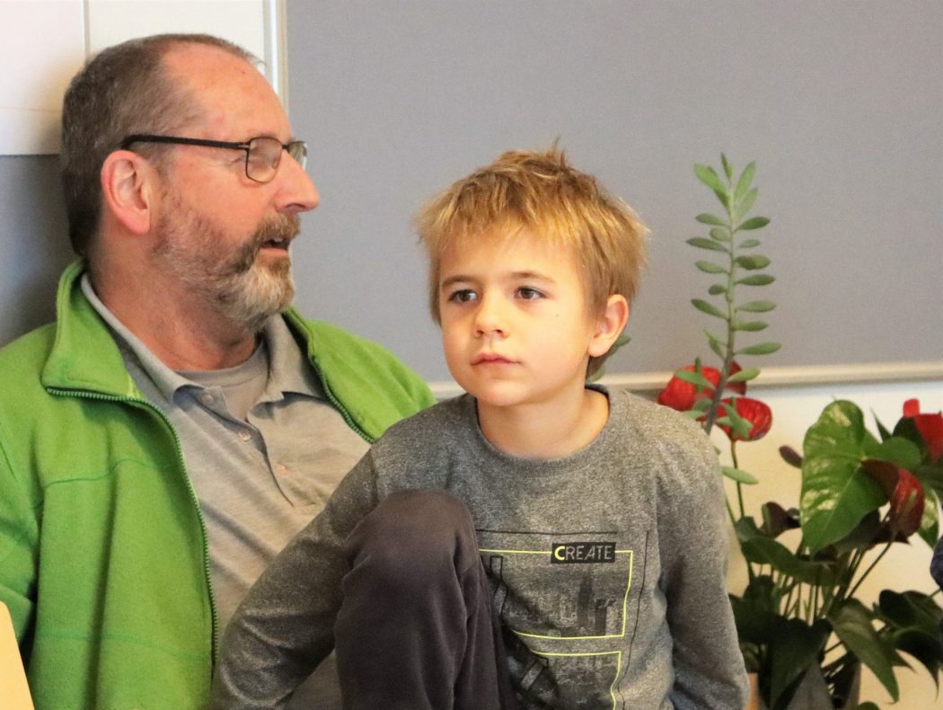 Mann sitzt mit 2 Kindern auf einer Bank